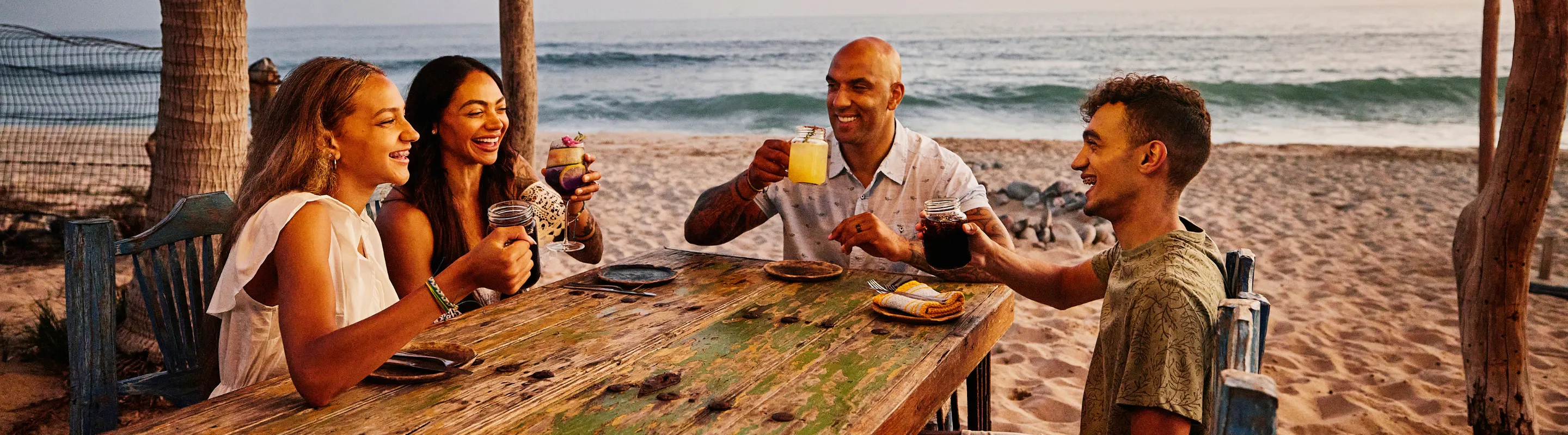 a family of four dines on a beach at a resort, insured with travel insurance for Mexico