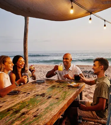 a family of four dines on a beach at a resort, insured with travel insurance for Mexico
