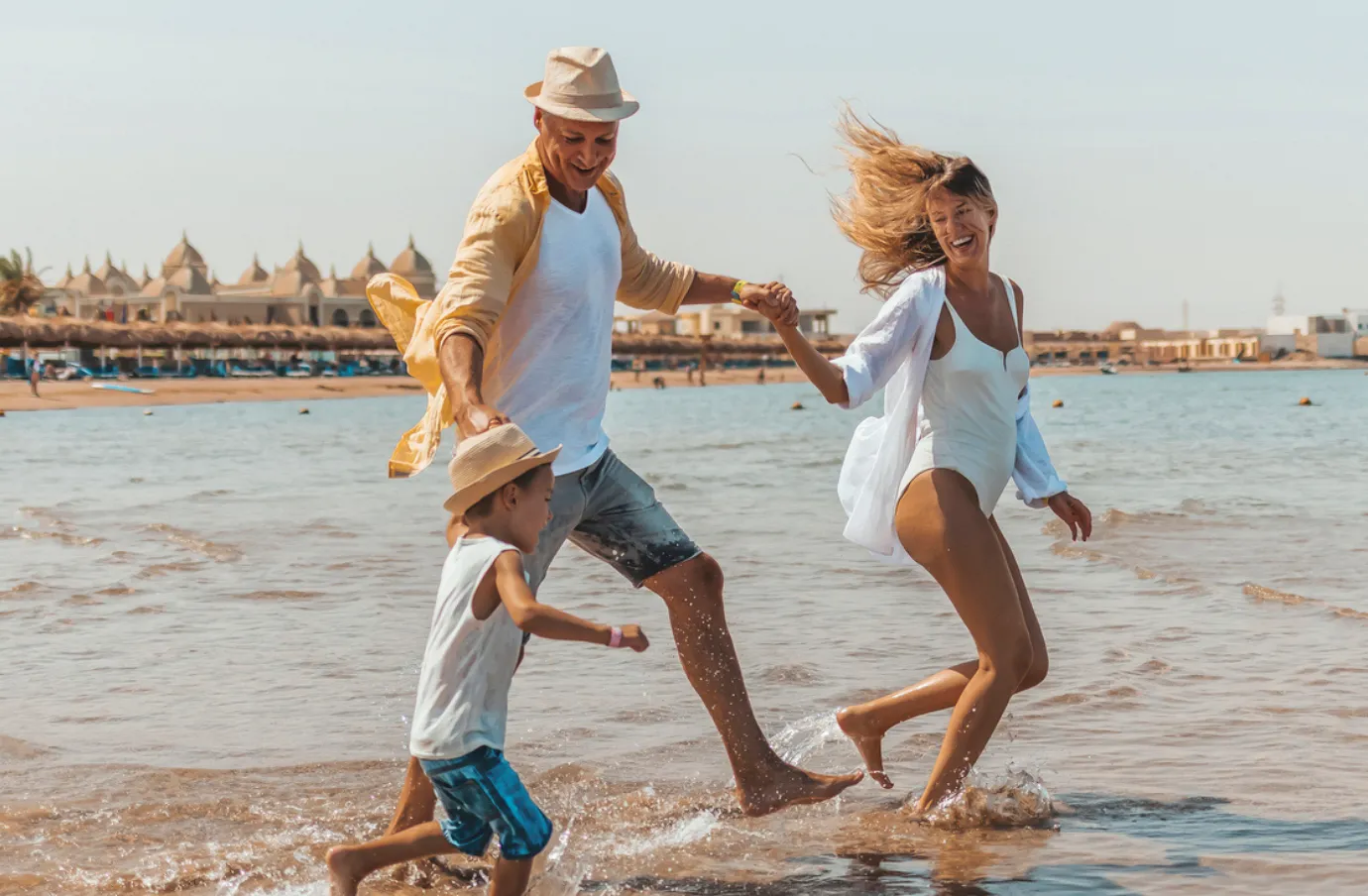 Parents and child running on the beach in Egypt on vacation after comparing travel insurance plans 