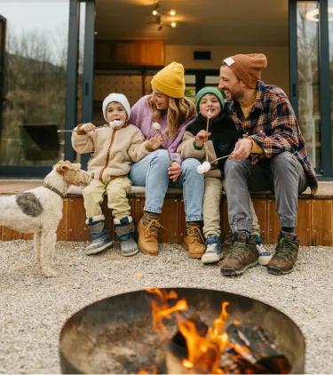 Parents with vacation rental travel insurance making smores at a cabin with their two young children