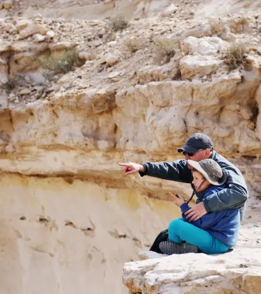a father and boy sit down to enjoy views on a desert hike, insured with travel insurance for Israel 