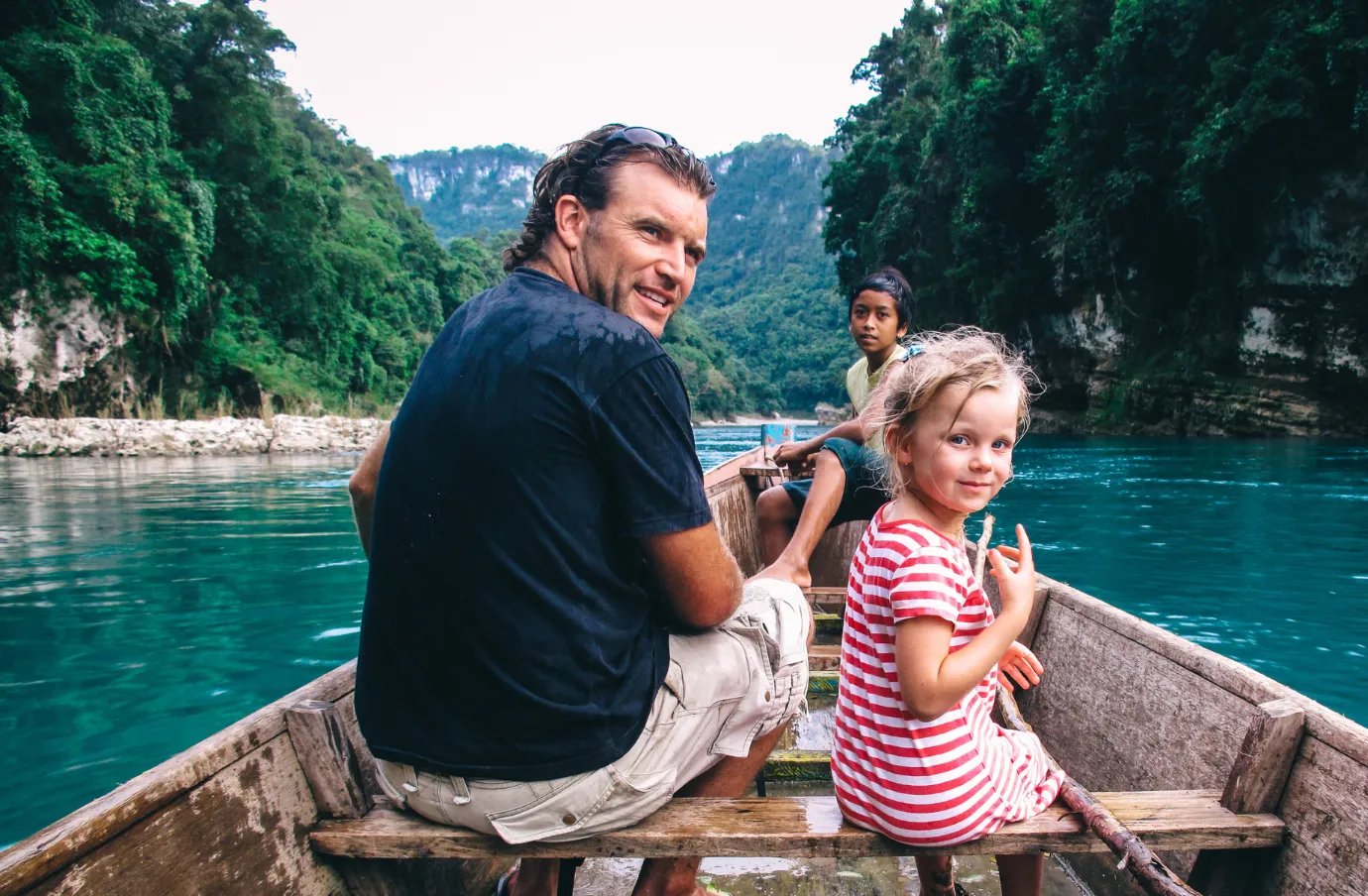 a father-daughter duo with travel insurance for the Philippines ride in a wooden boat along a turquoise water