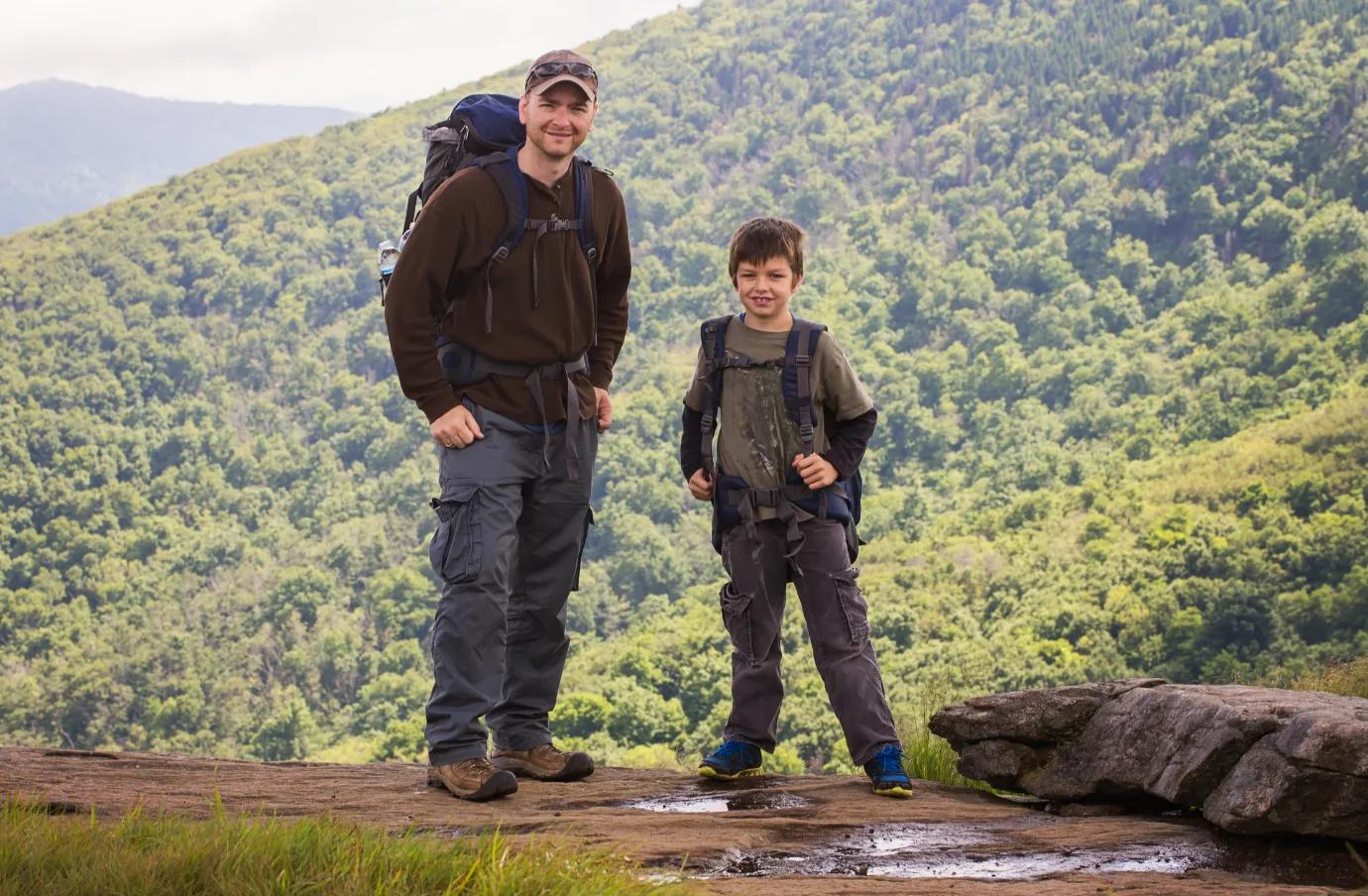 a father and son smile as they hike the Great Smoky Mountains, insured with travel insurance for Tennessee
