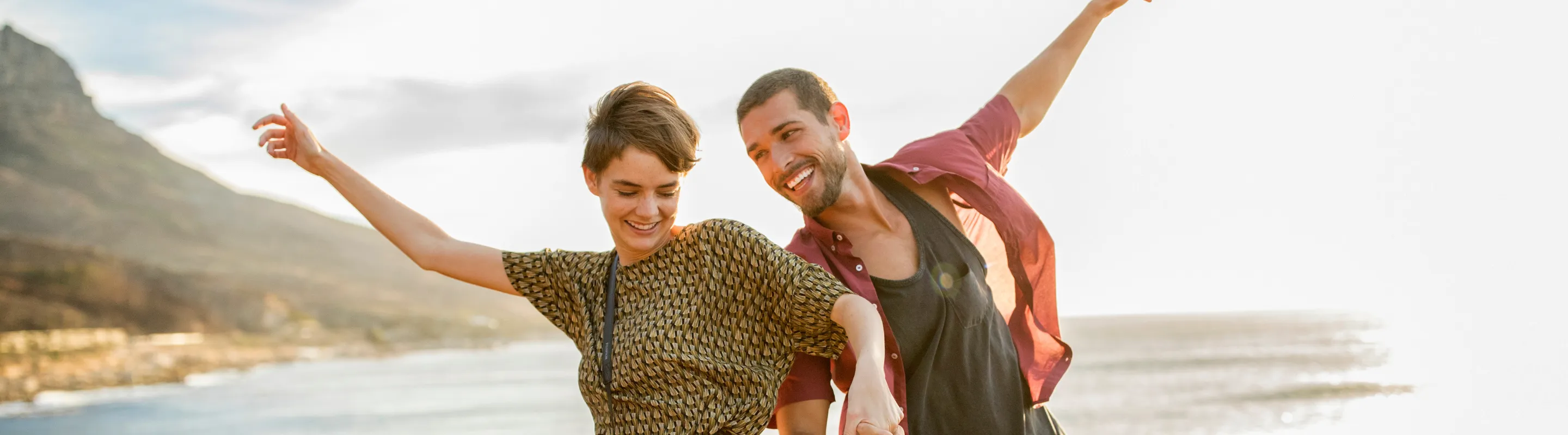 two friends laugh and explore a coastal trail at sunset in Cape Town, insured with travel insurance for Africa 