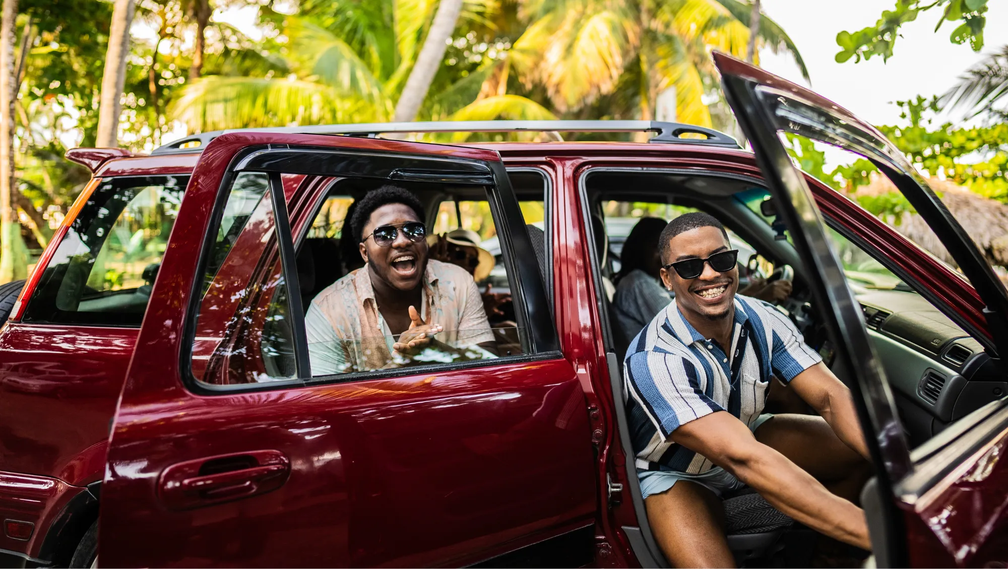 a group of friends sit in a parked SUV surrounded by palm trees, hoping to avoid a vehicle accident on vacation 