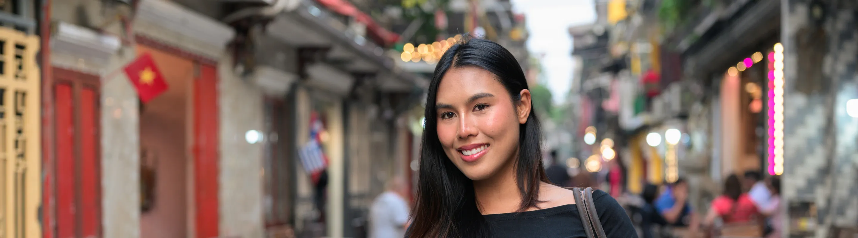 a woman with travel insurance for Vietnam walks along Hanoi Train Street, lined with cafés and traditional buildings