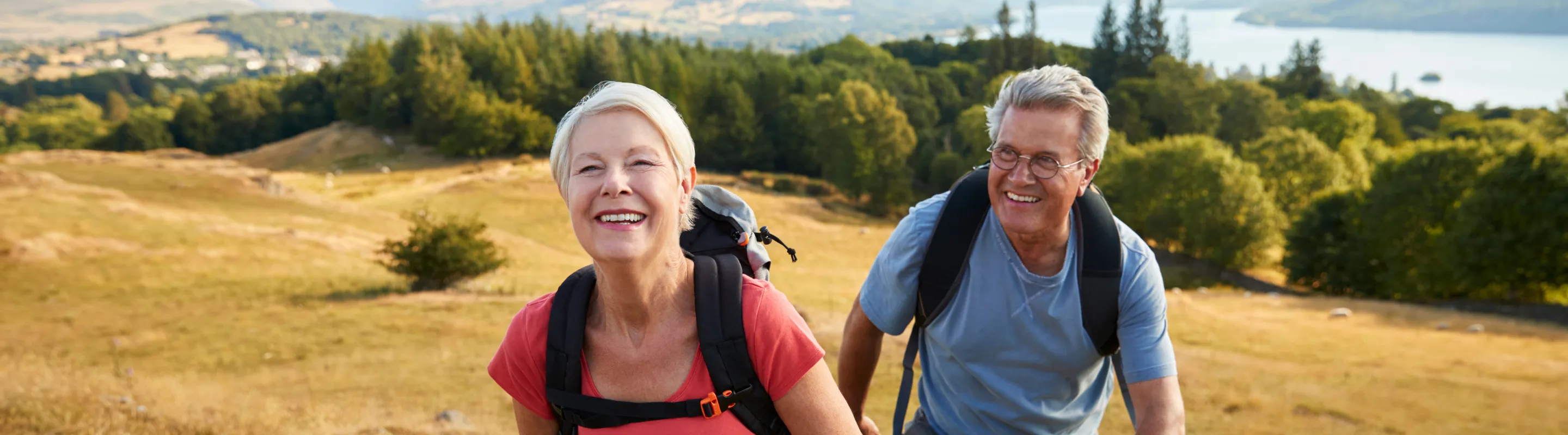 a senior couple with travel insurance for the UK hikes through the Lake District National Park on a sunny day