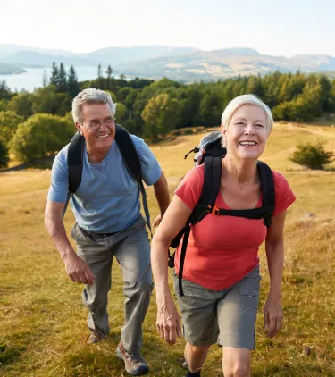 a senior couple with travel insurance for the UK hikes through the Lake District National Park on a sunny day