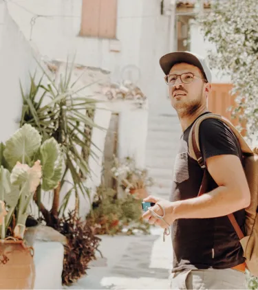 a young man walks through a neighborhood in Athens on vacation, insured with travel insurance for Greece 
