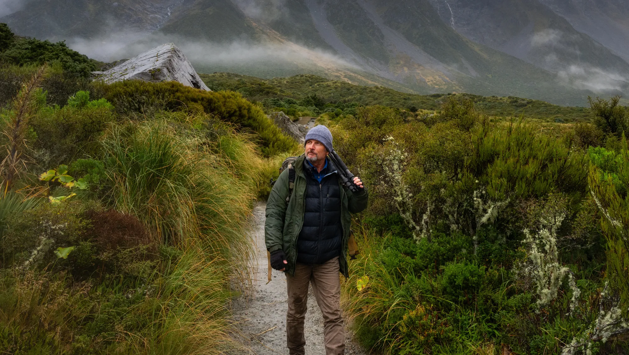 a man hikes beneath misty mountains on vacation after researching responsible traveler best practices