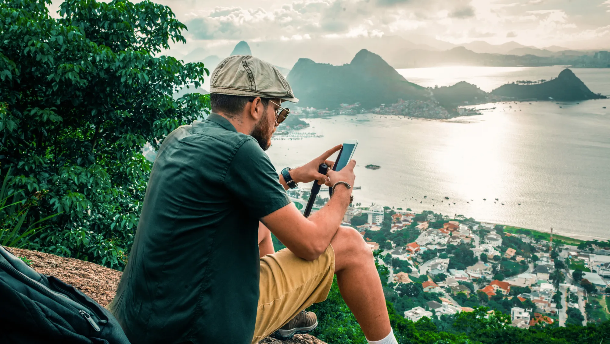 a man looks at the travel app on his phone during his hike in Rio de Jeneiro