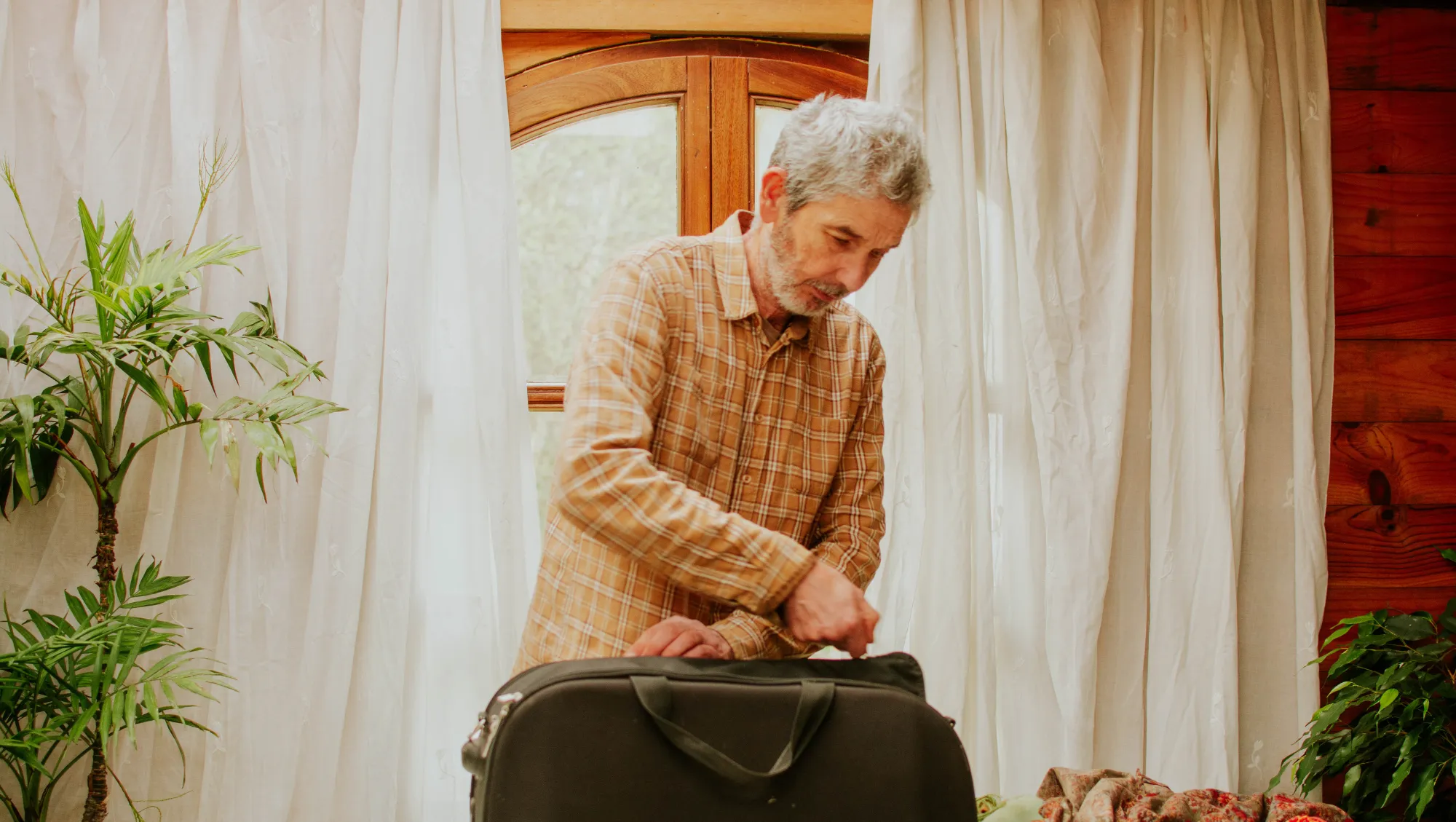 an older man zips up his suitcase, hoping to avoid having his personal belongings stolen on vacation 