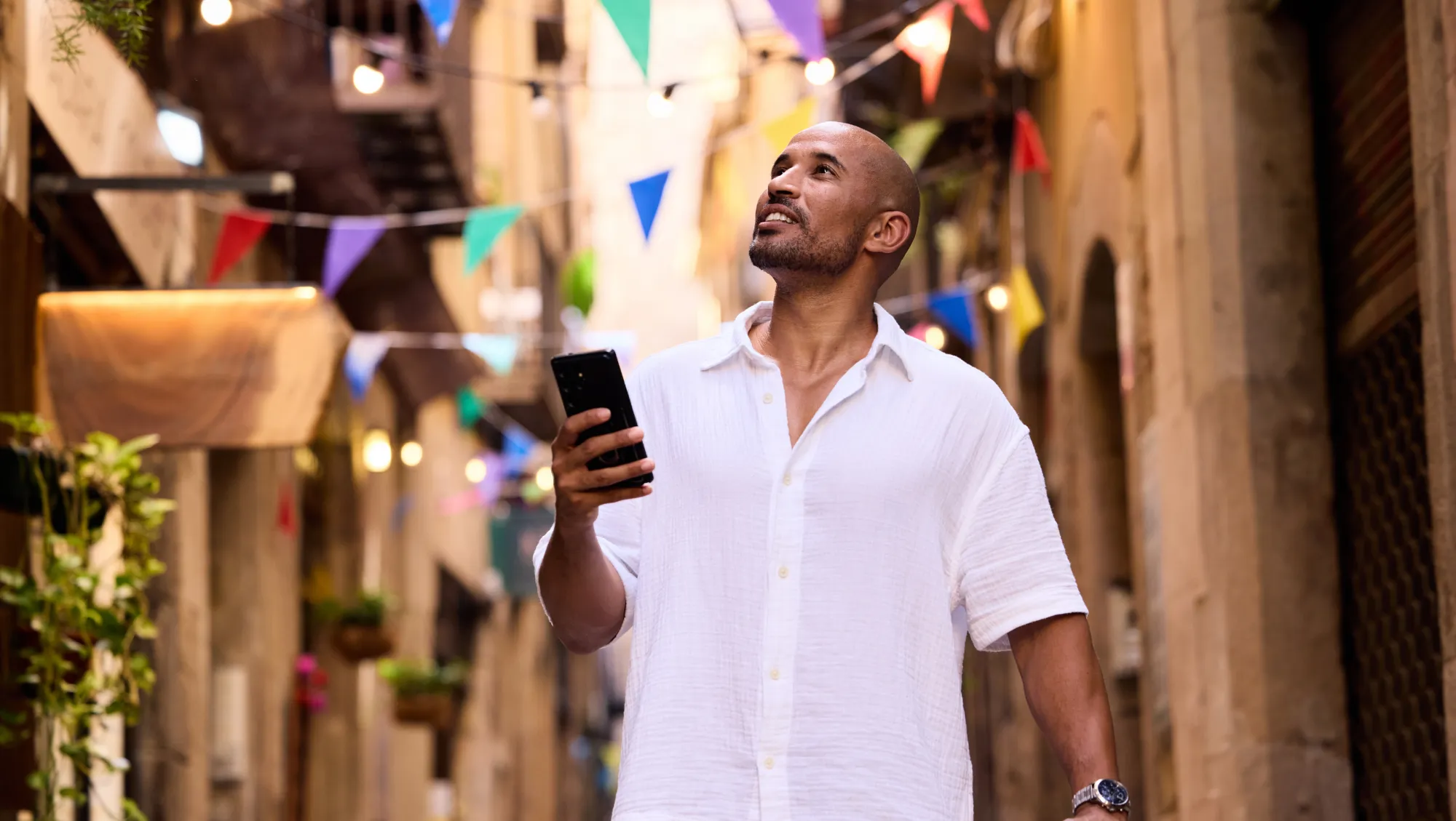 a man looks at the travel app on his phone as he walks through the streets of Barcelona, Spain