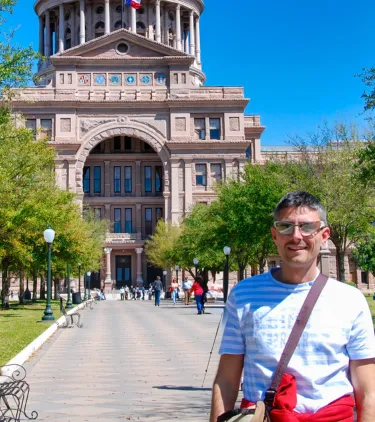 a middle-aged man with travel insurance for Texas stands in front of the Texas State Capitol in Austin 