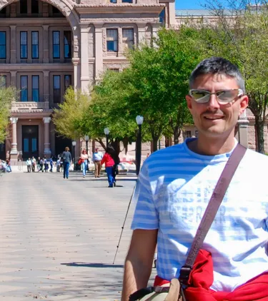 a middle-aged man with travel insurance for Texas stands in front of the Texas State Capitol in Austin 