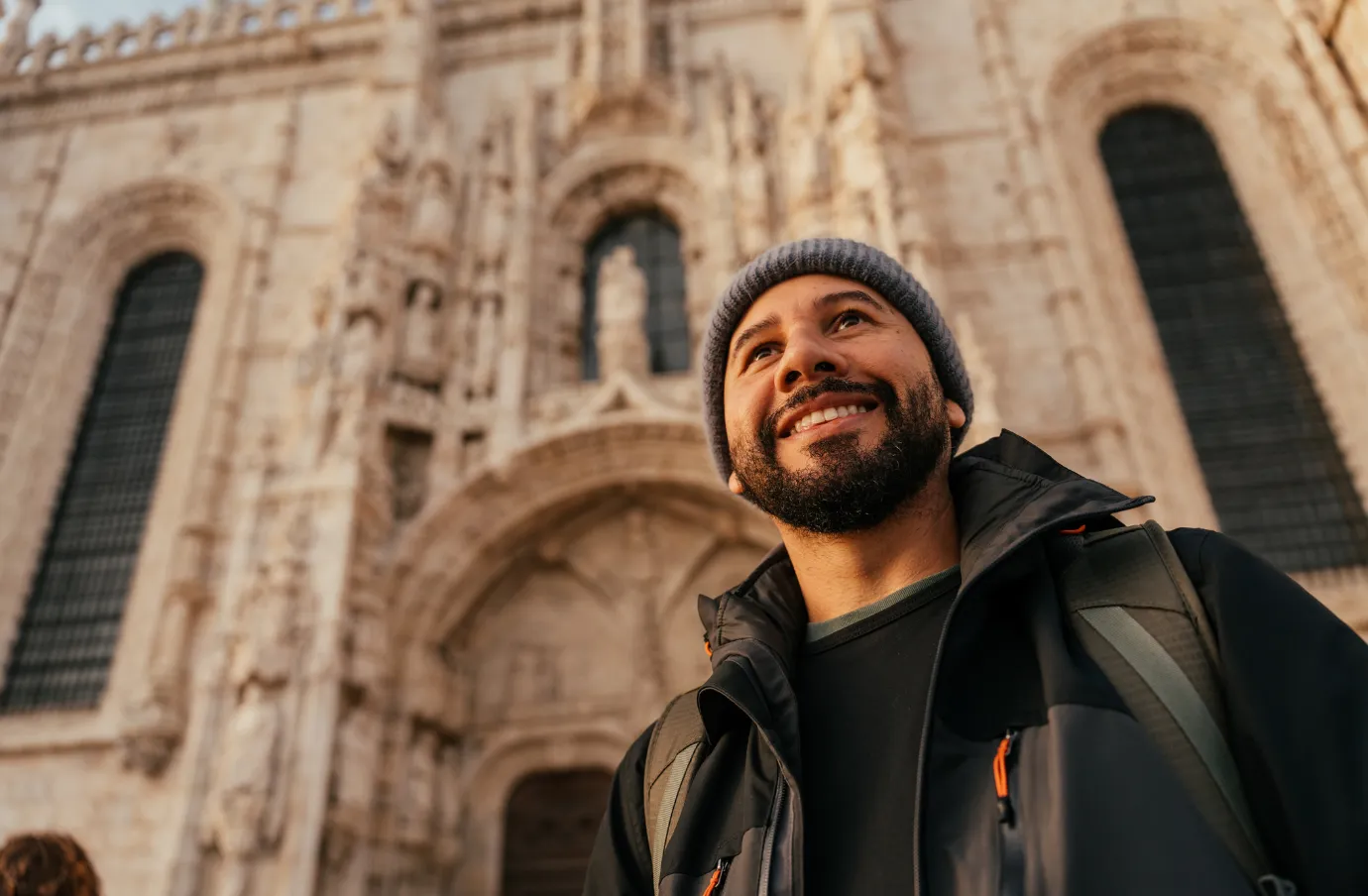 a man stands in front of the Jeronimos Monastery in Lisbon, insured with travel insurance for Europe
