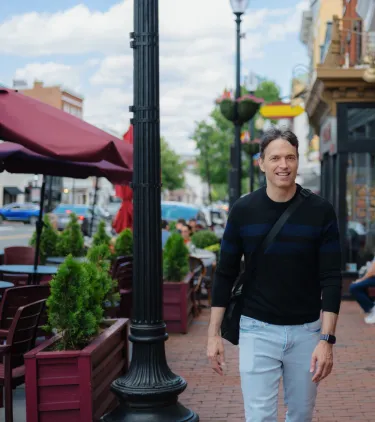 a man with travel insurance for Washington, D.C. walks along a brick sidewalk lined with restaurants, shops, and outdoor seating