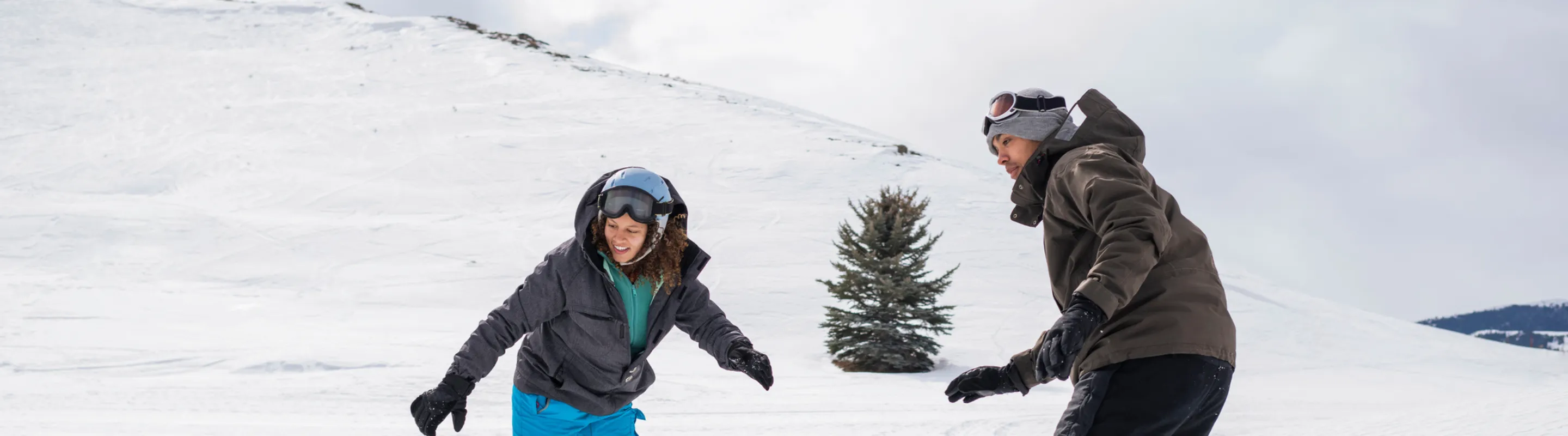 a young man and woman snowboard down a snowy slope on a winter vacation after researching snowboard and ski insurance