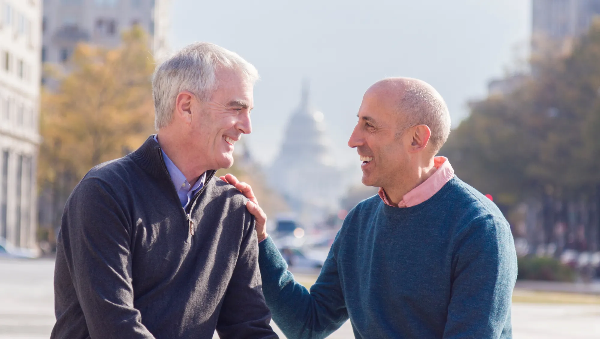 a couple sits and talks near Capitol Hill, Washington, D.C. on vacation after reading our LGBTQ travel tips