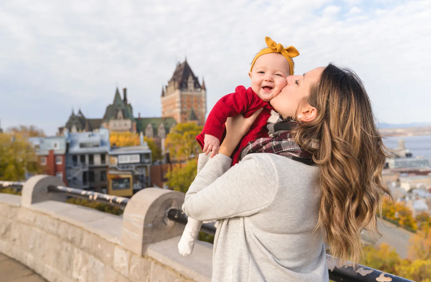 a mother holds and kisses her baby in Quebec City on vacation, insured with travel insurance for Canada