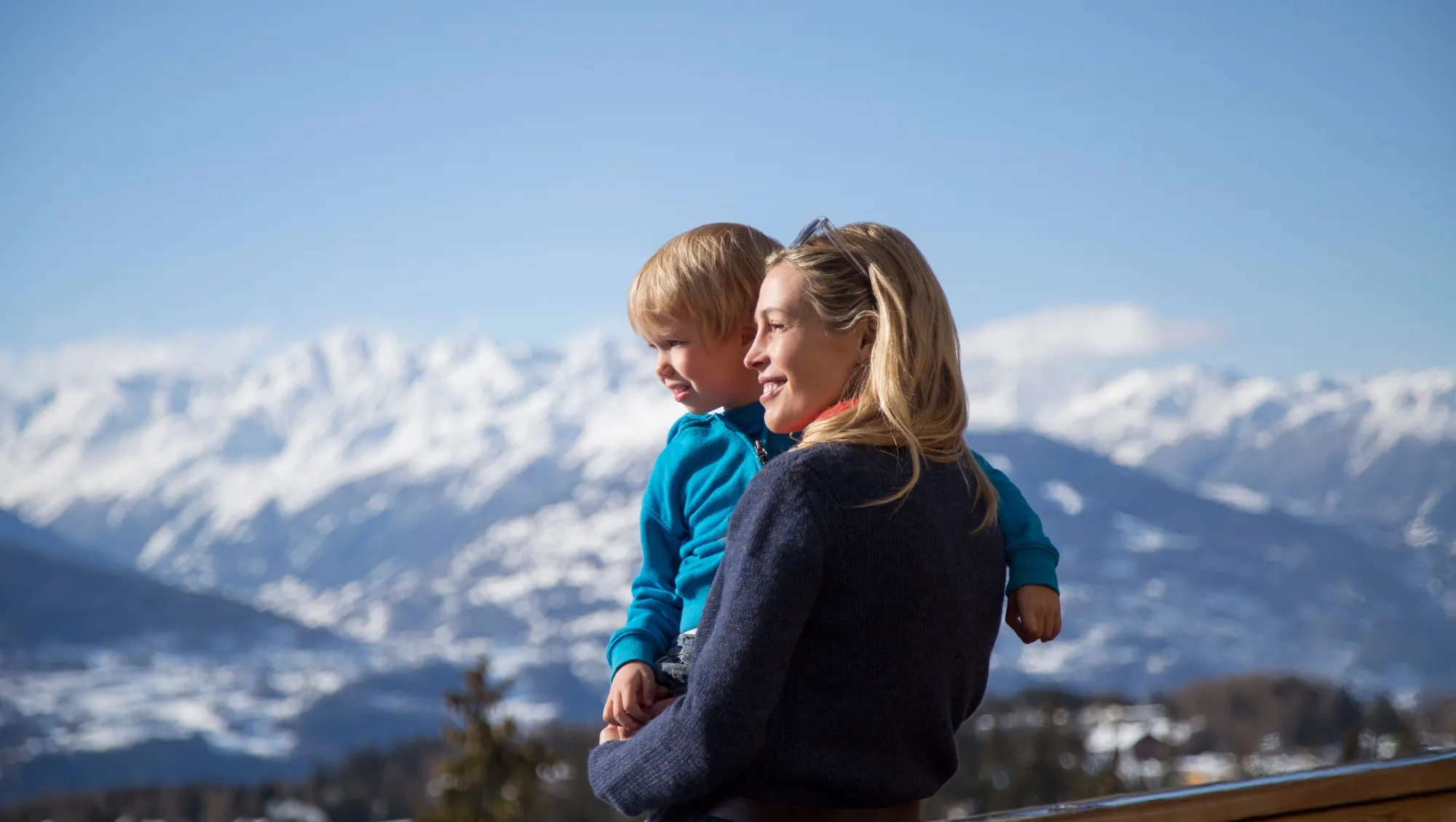 a mother holds her son near a mountain on vacation after researching responsible traveler best practices 