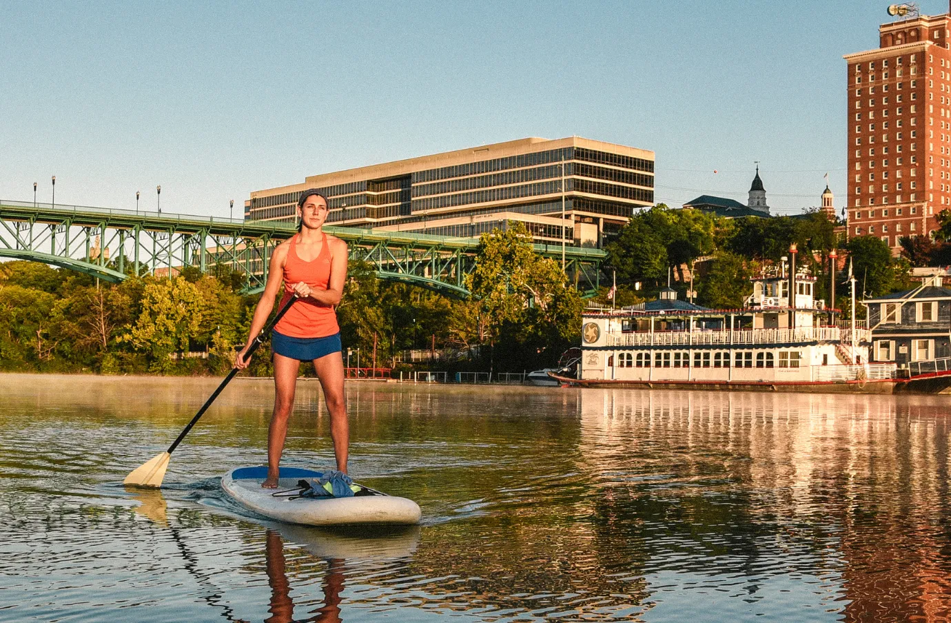 a woman paddleboards on the river near Knoxville, insured with travel insurance for Tennessee