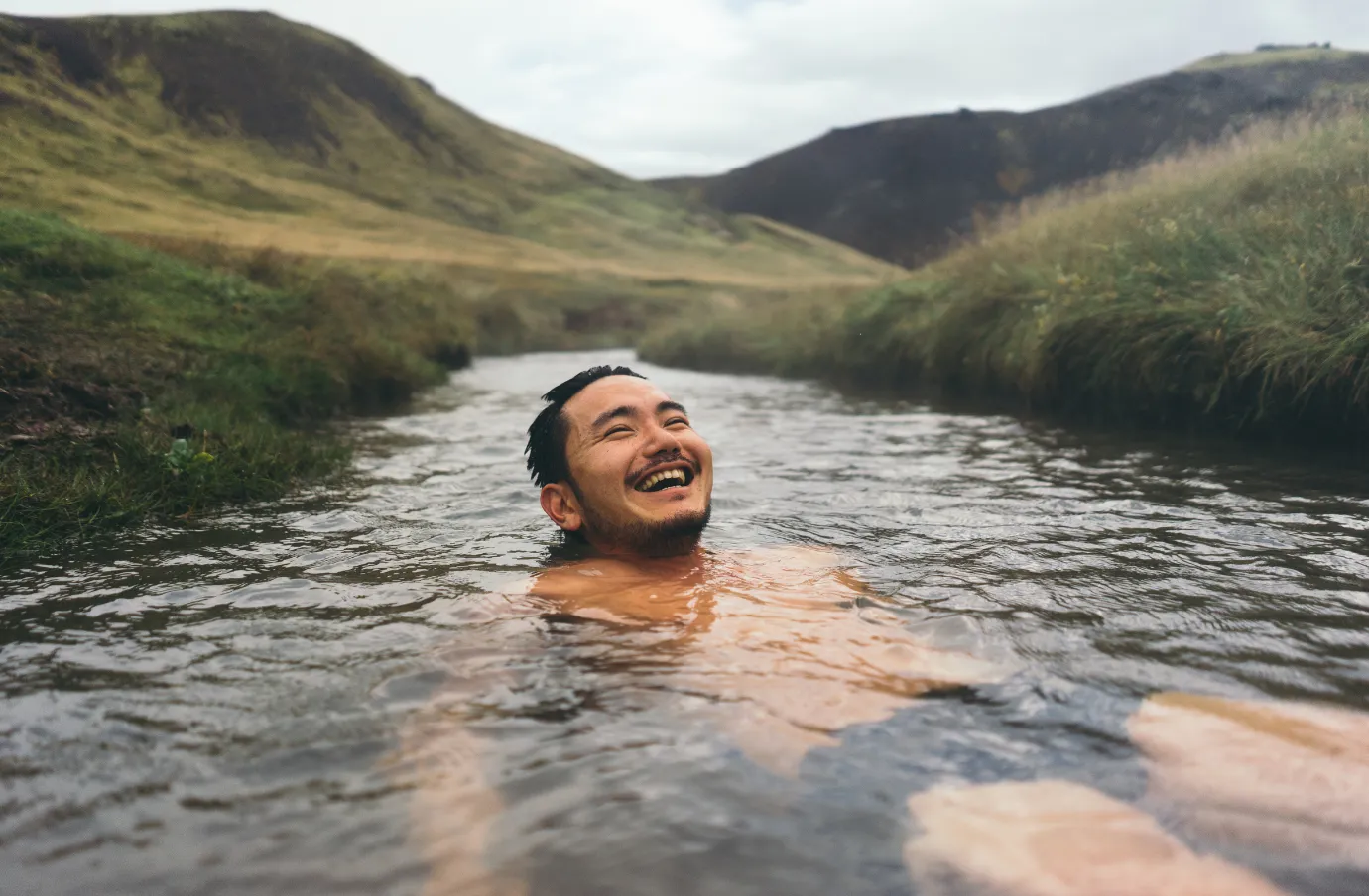 a man with long-term travel insurance relaxes in a natural hot spring