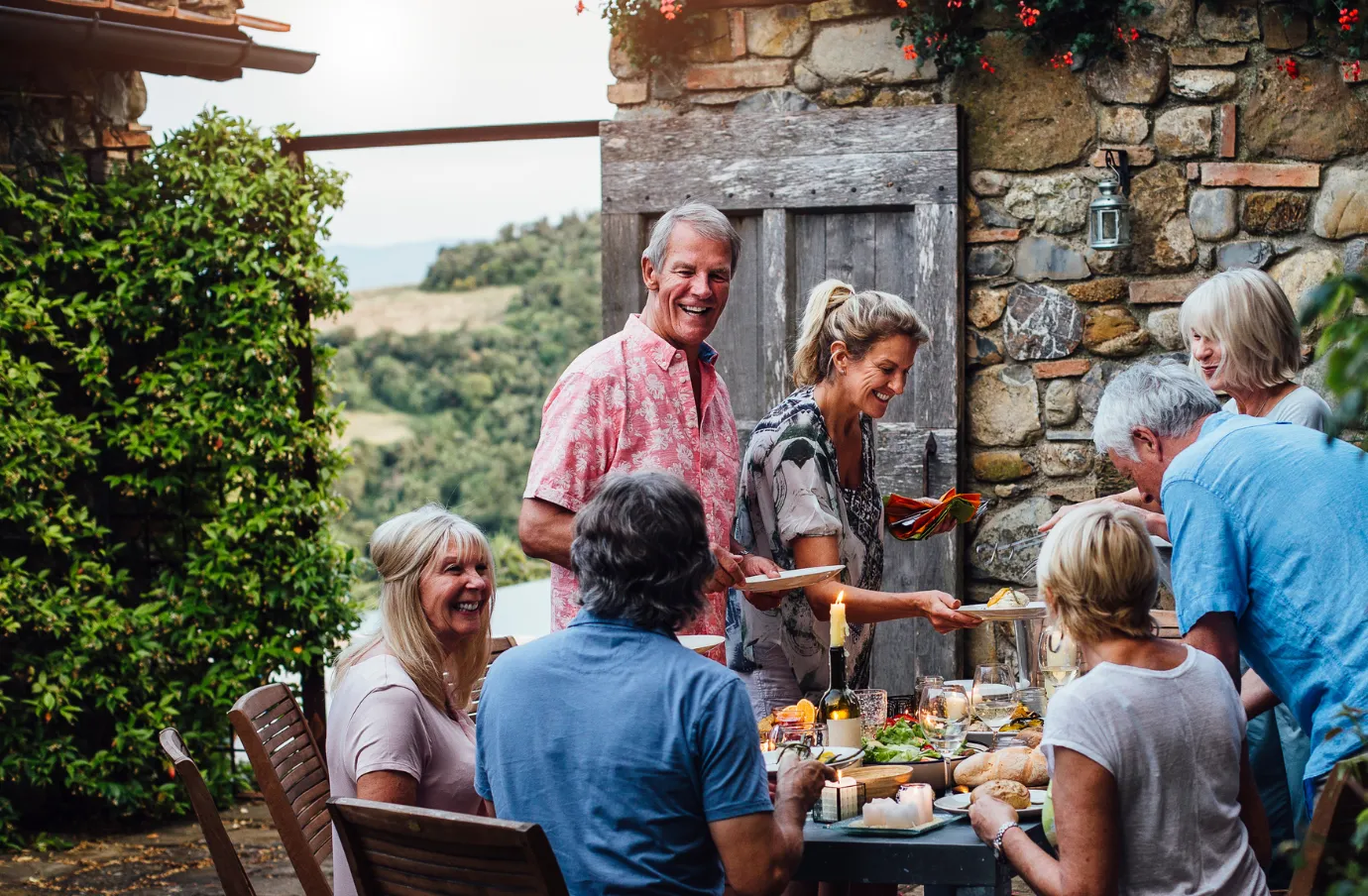 senior friends dine together in Tuscany's countryside, insured with travel insurance for Italy