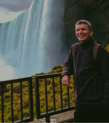 a male tourist smiles on a lookout point at Niagara Falls, insured with travel insurance for Canada