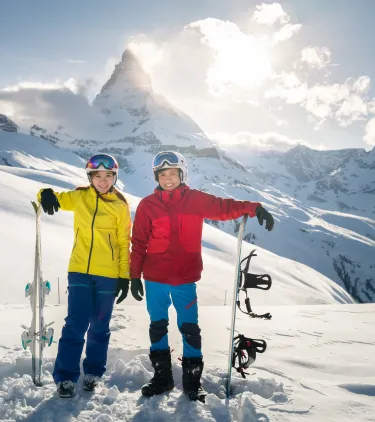 two female snowboarders pose in front of the Matterhorn, insured with travel insurance for Switzerland 