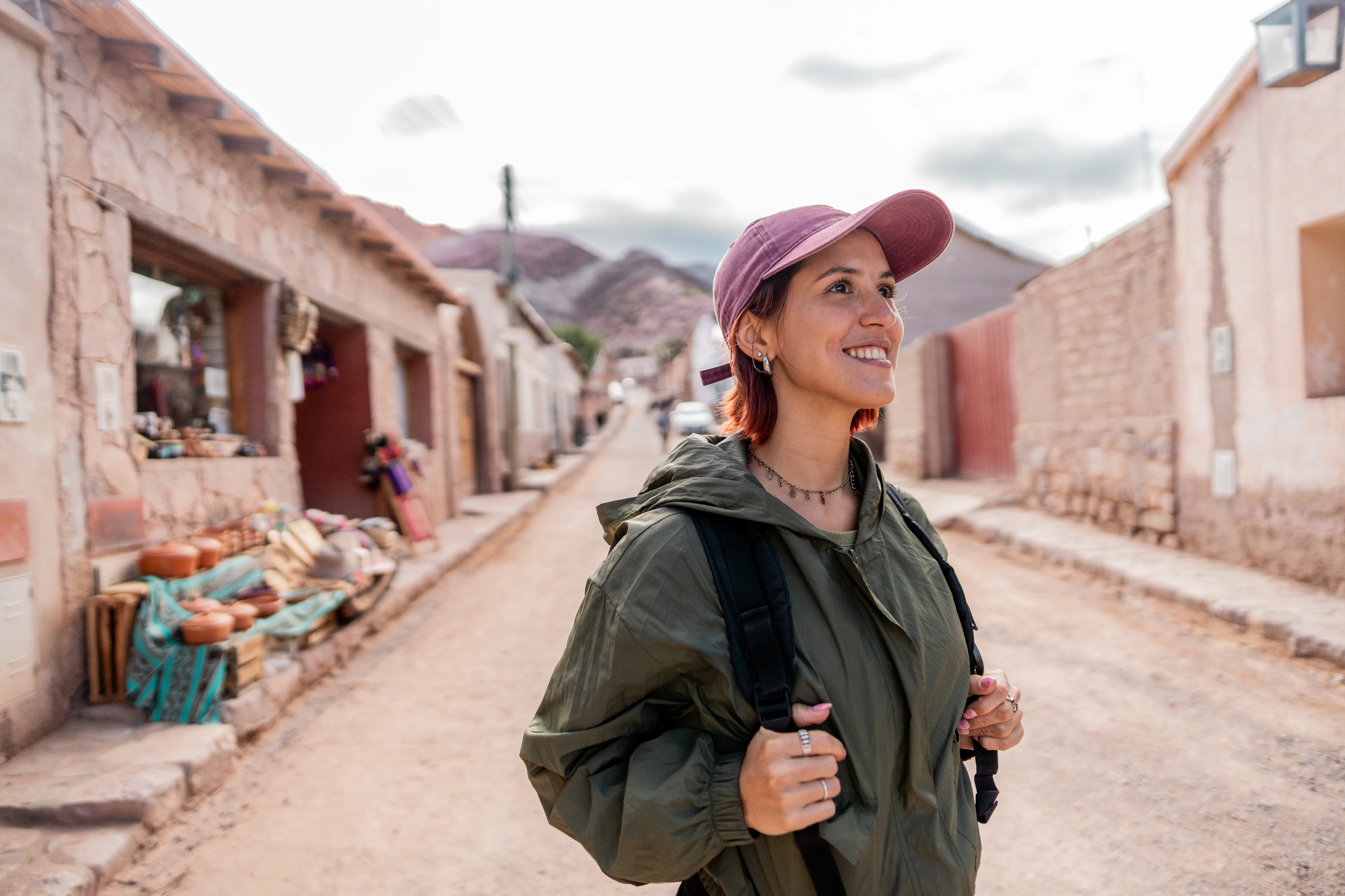 a woman with travel insurance walks through a historic village street lined with traditional stone buildings