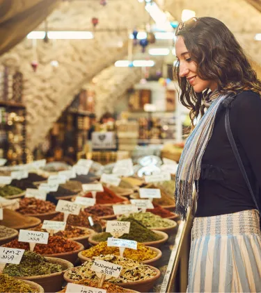 a woman browses spices at a market, insured with travel insurance for Israel