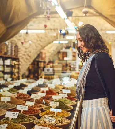 a woman browses spices at a market, insured with travel insurance for Israel