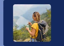 Woman hiking in the mountains with a backpack and reusable water bottle, shown in Travelex Insurance's newsroom