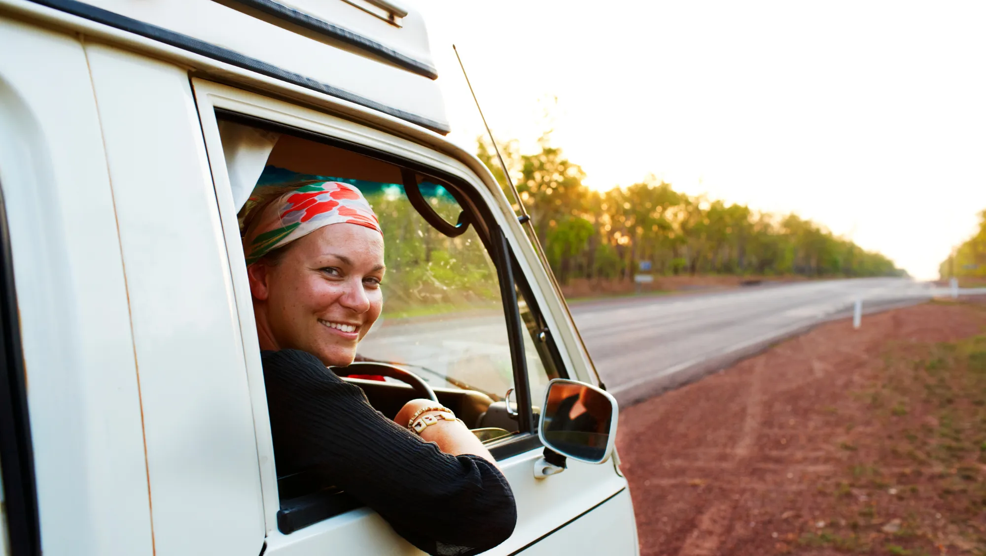 a female traveler sits in a camper van in Australia, knowing what to do if she's in a vehicle accident on vacation 
