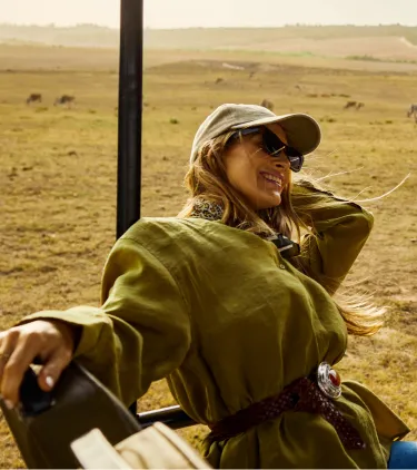 traveling young adult friends sit on an open-air safari vehicle, insured with travel insurance for Africa 