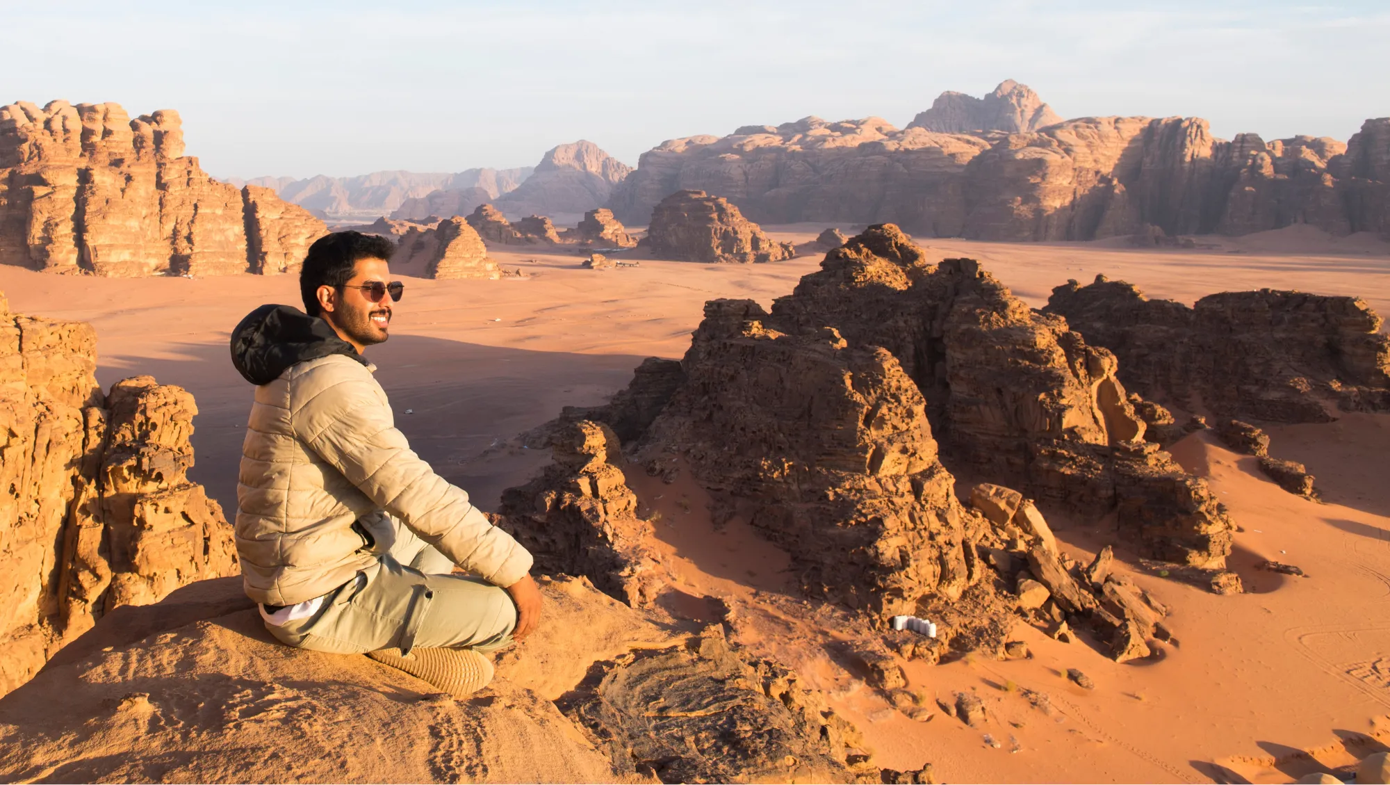 a man sits in the Wadi Rum Desert, Jordan, with a travel app in his pocket in case he has to call for help