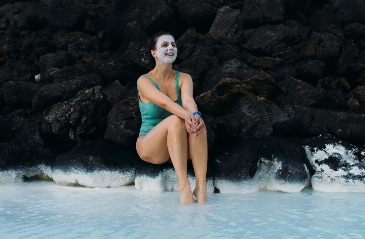 a woman relaxes at the Blue Lagoon with a facemask on, insured with travel insurance for Iceland