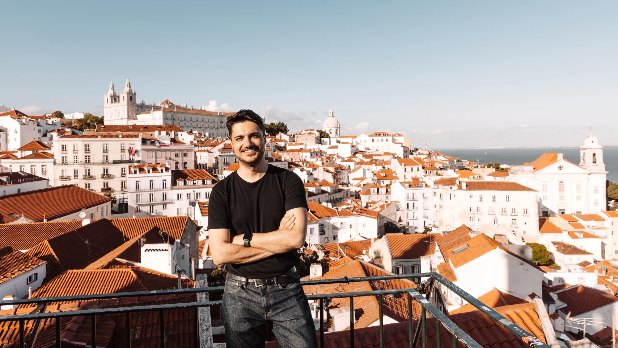 a man stands on an overlook of Lisbon, Portugal, leaving his valuables in his hotel to avoid theft on vacation
