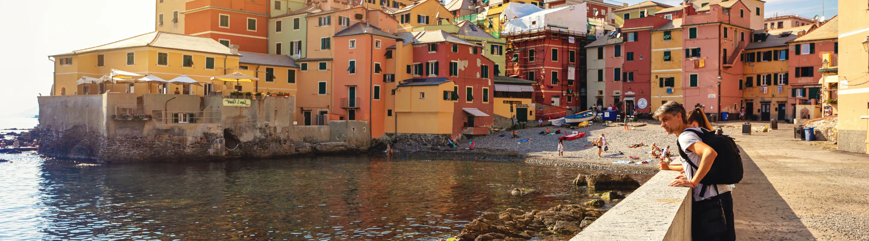 two young travelers admire the waterfront in Boccadasse, Italy, insured with travel insurance for Europe