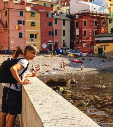 two young travelers admire the waterfront in Boccadasse, Italy, insured with travel insurance for Europe