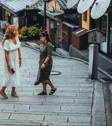 two female travelers walk through the traditional streets of Kyoto, Japan, insured with travel insurance for Japan
