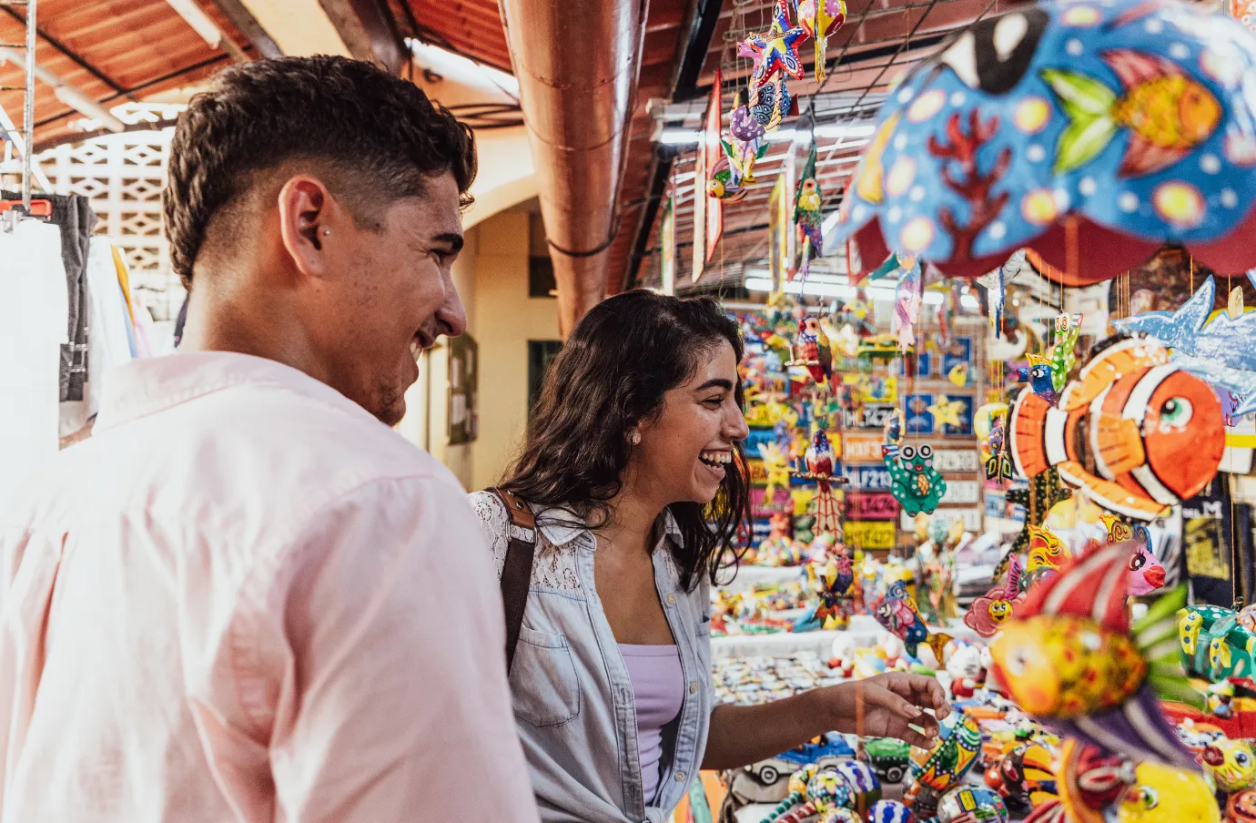a couple with travel insurance for the Caribbean browses colorful souvenirs at a local artisan market