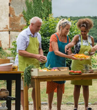 middle-aged travelers take a cooking class in the French countryside, insured with travel insurance for France 