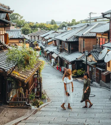 two female travelers walk through the traditional streets of Kyoto, Japan, insured with travel insurance for Japan