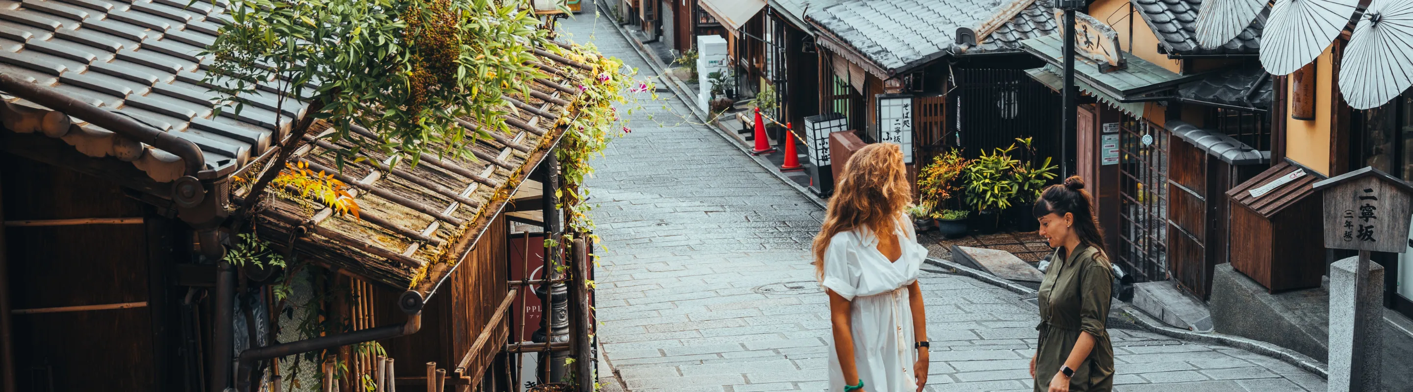two female travelers walk through the traditional streets of Kyoto, Japan, insured with travel insurance for Japan