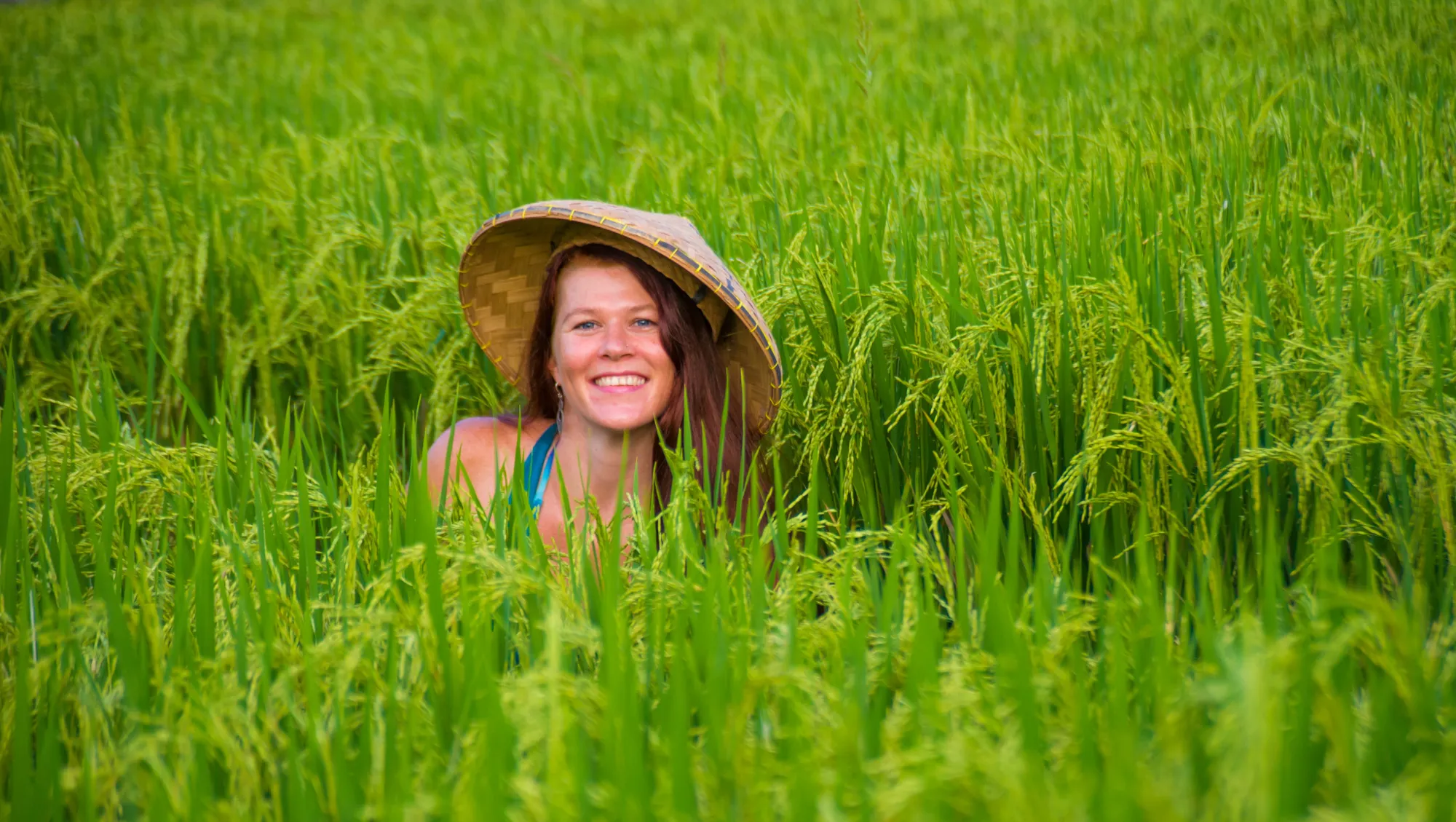 a woman sits among lush green rice fields on vacation in Vietnam after researching responsible traveler best practices 