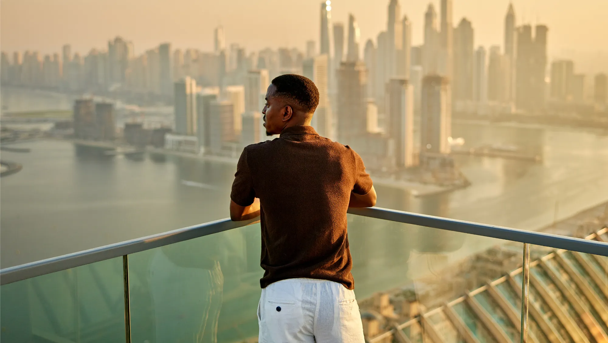 a man stands on an observation deck overlooking Dubai's waterfront skyline after reading our LGBTQ travel tips