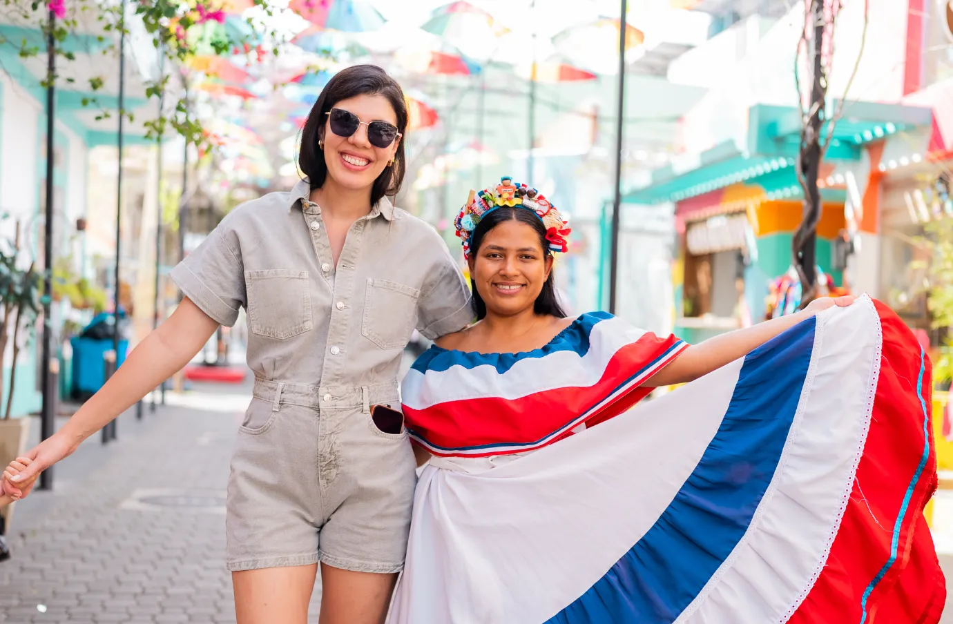 a woman with travel insurance for the Dominican Republic poses with a performer in traditional dress on a colorful street