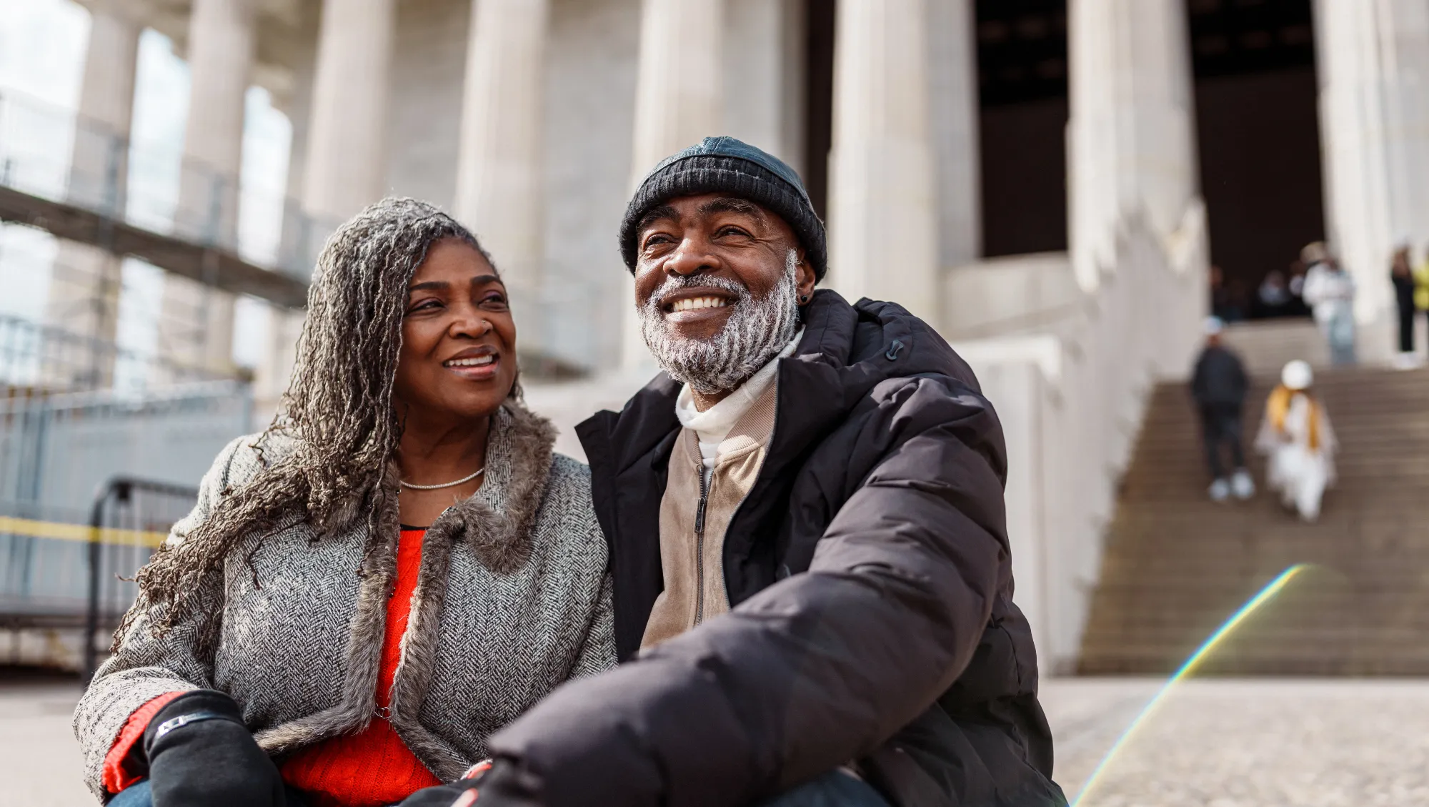 a senior black couple sits outside the Lincoln Memorial after researching, "Does travel insurance cover terrorism?"